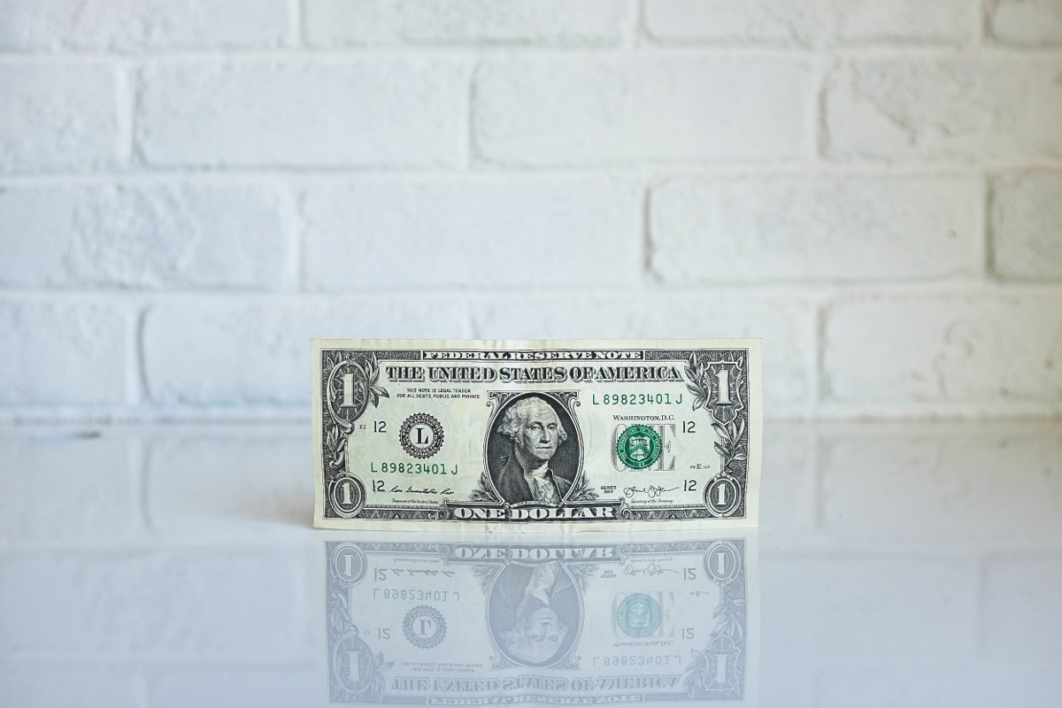 US one-dollar bill photographed against a wall, shown as generic money context.